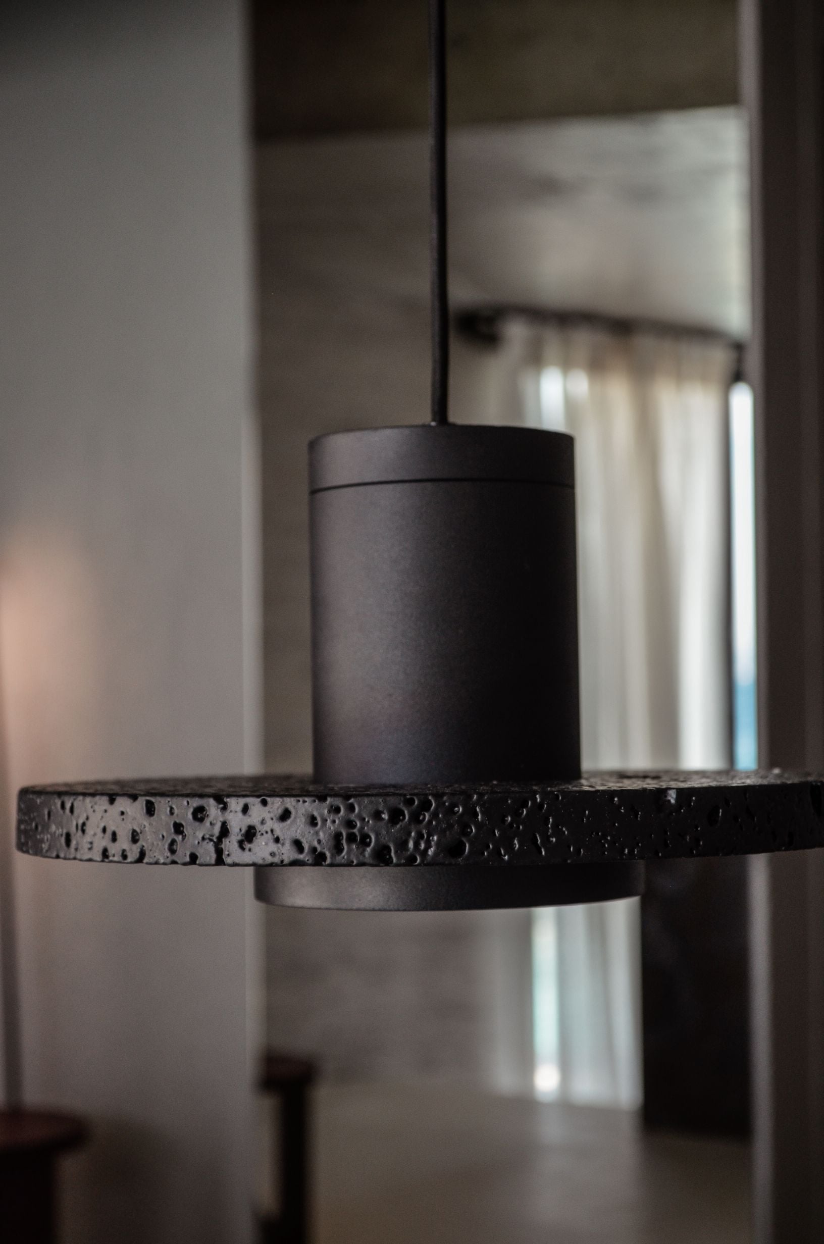 Dark sculptural ornament on a shelf beside a cylindrical metal feature — Amoni