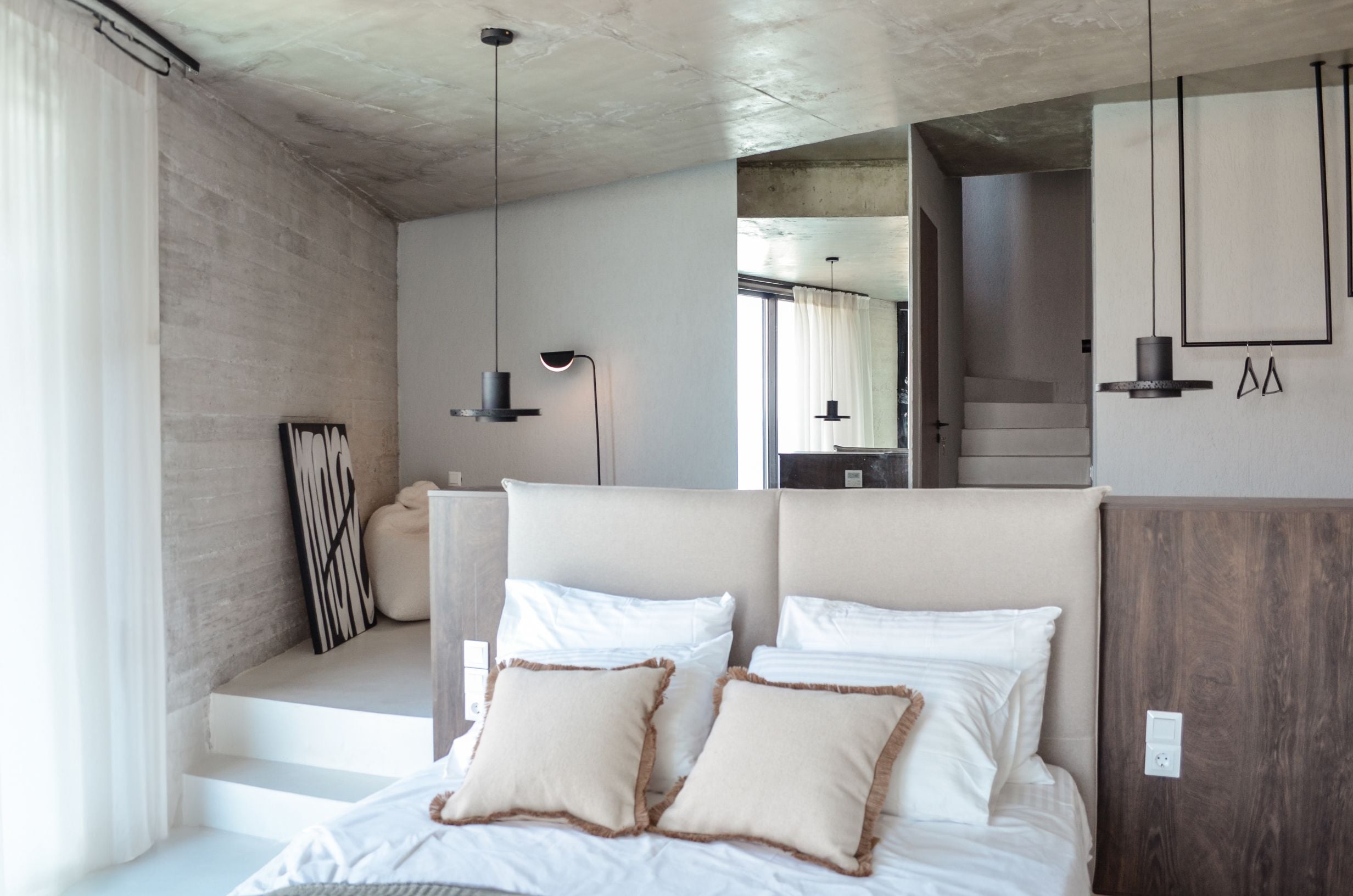 Bedroom with white bedding, timber cabinetry and exposed concrete — Amoni