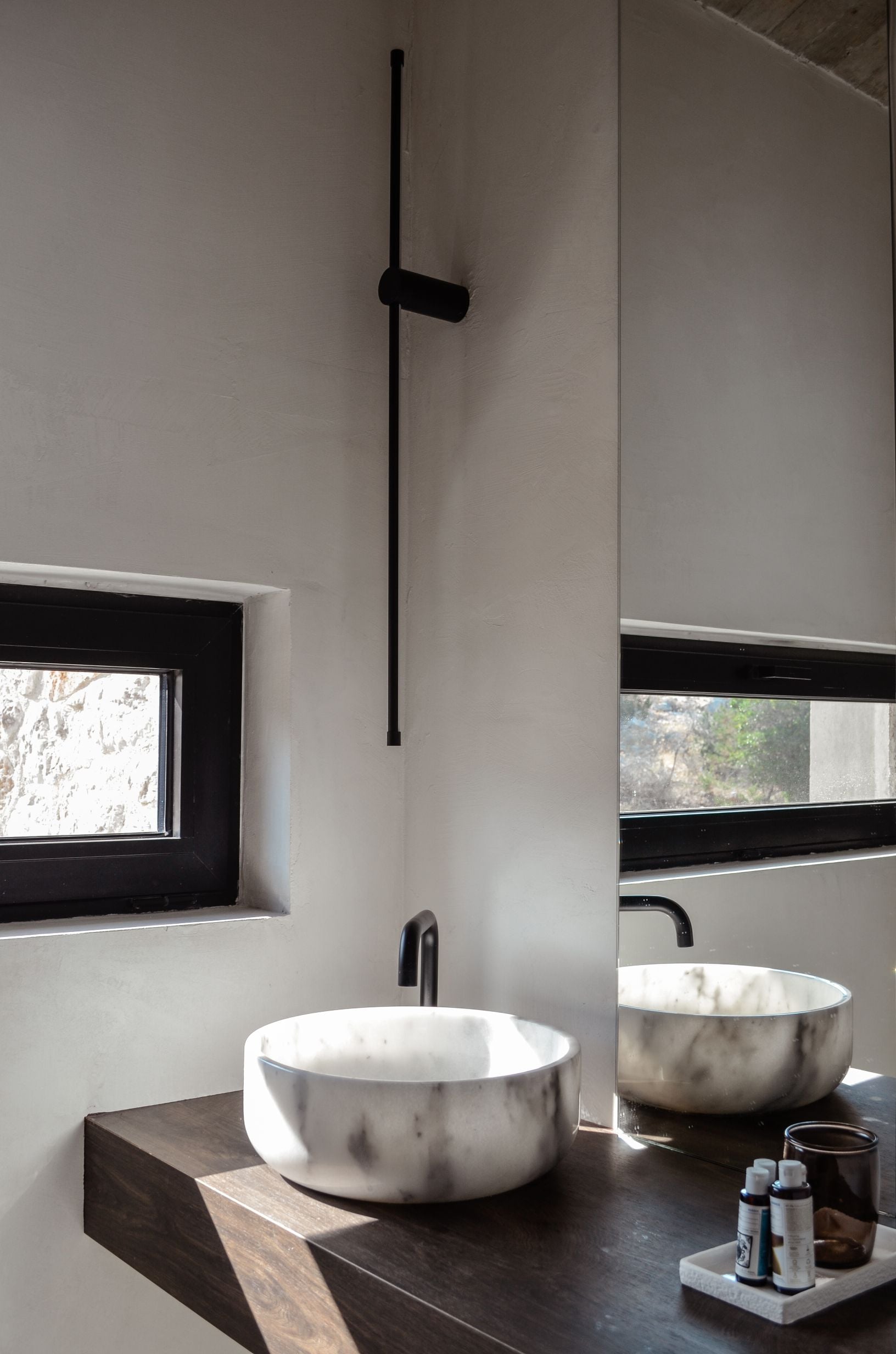 Round bathroom basin on a dark vanity beneath a tall mirror — Amoni