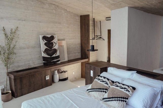 Bedroom with a timber console, sculptural artwork and exposed concrete — Amoni
