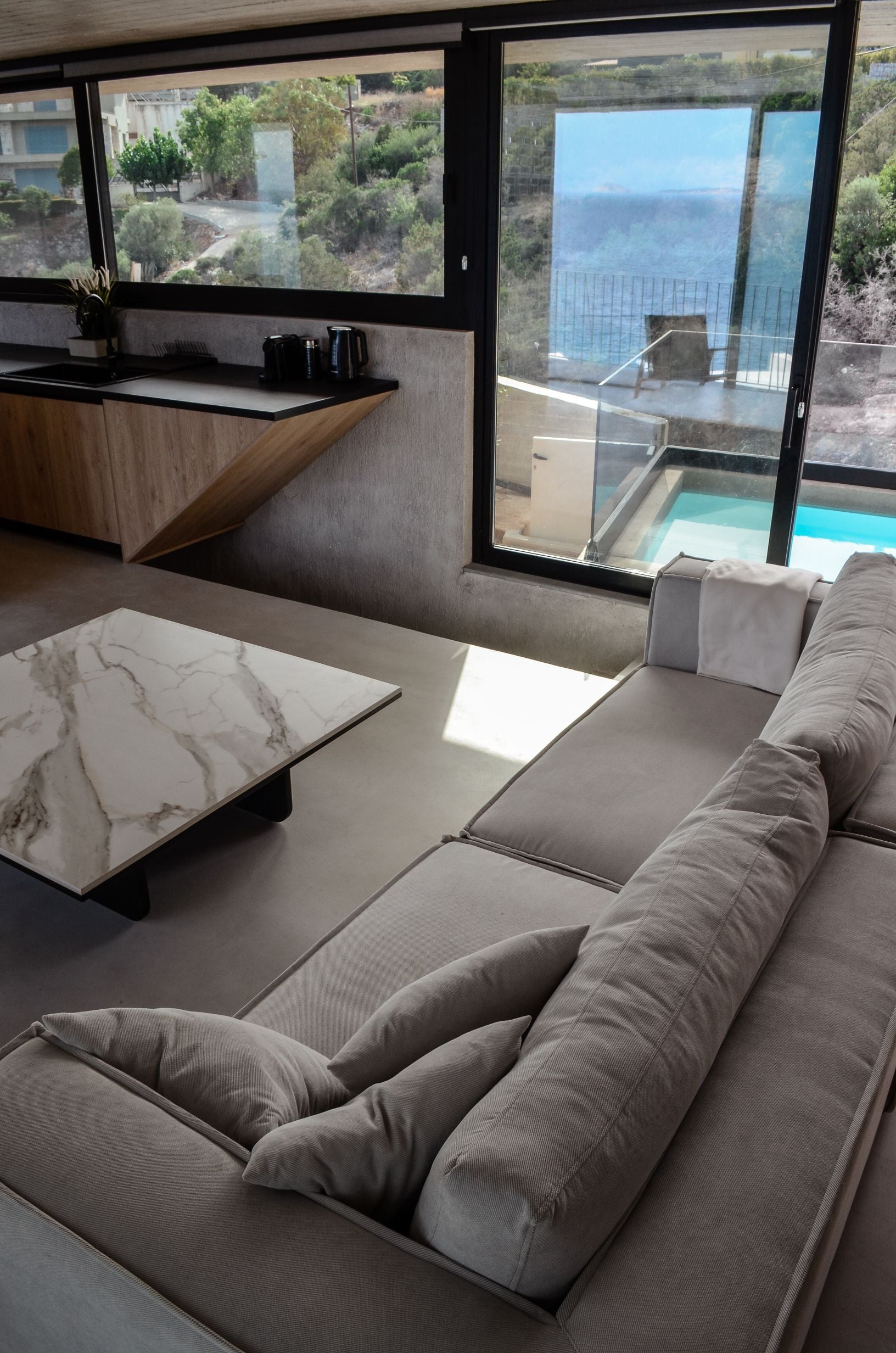 Living area with pale cushions opening onto an outdoor pool — Amoni