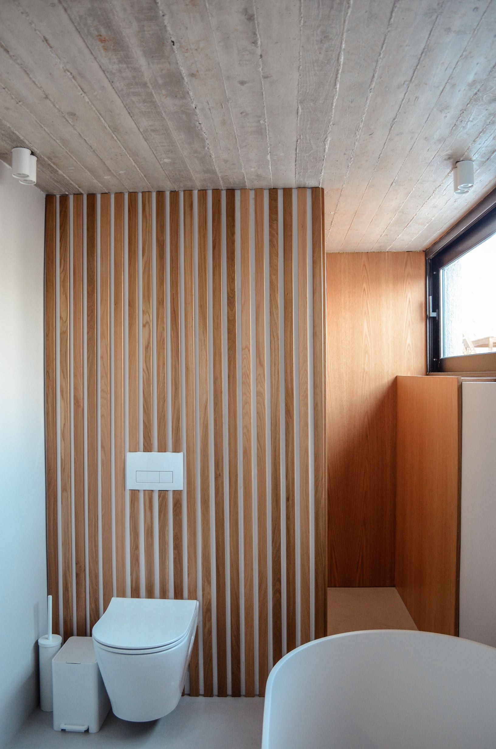 Bathroom with vertical timber wall panels and a wall-hung toilet — Amoni
