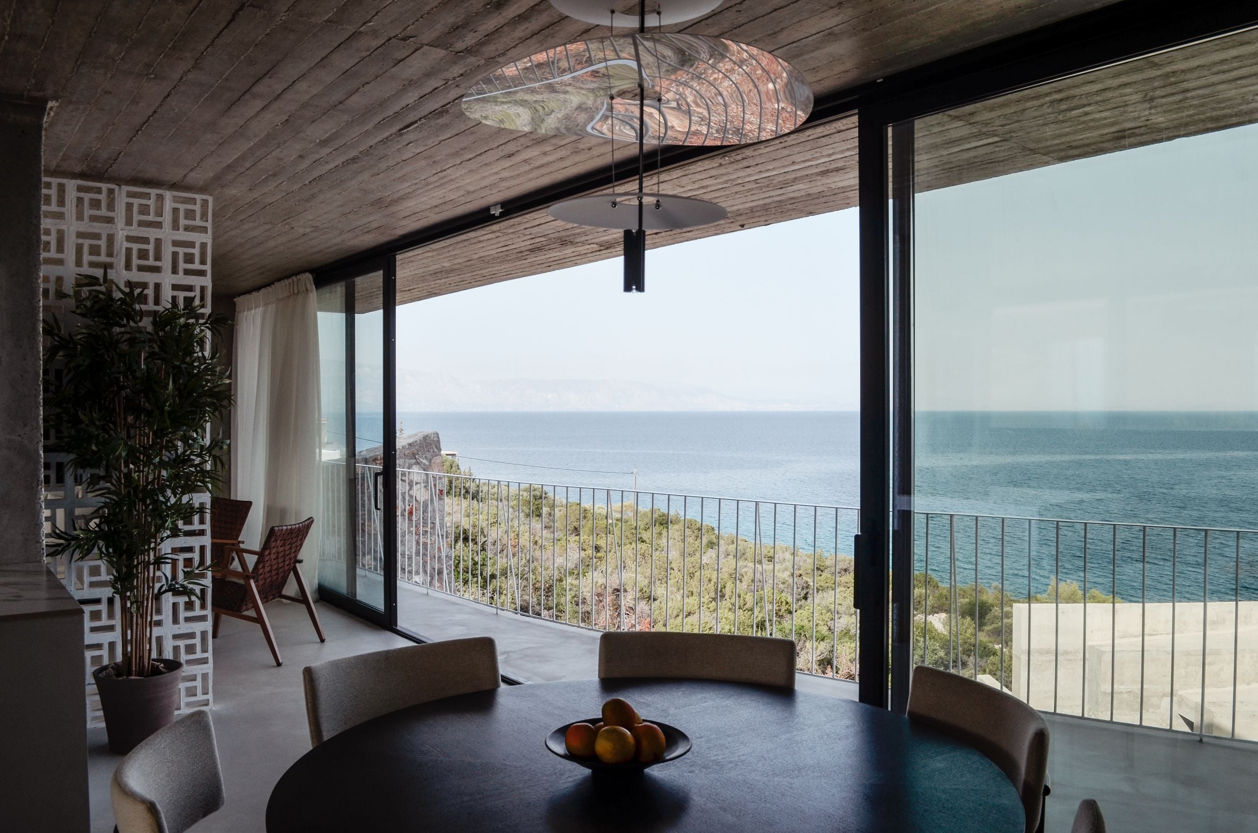 Dining table beside floor-to-ceiling glazing with a panoramic sea view — Amoni