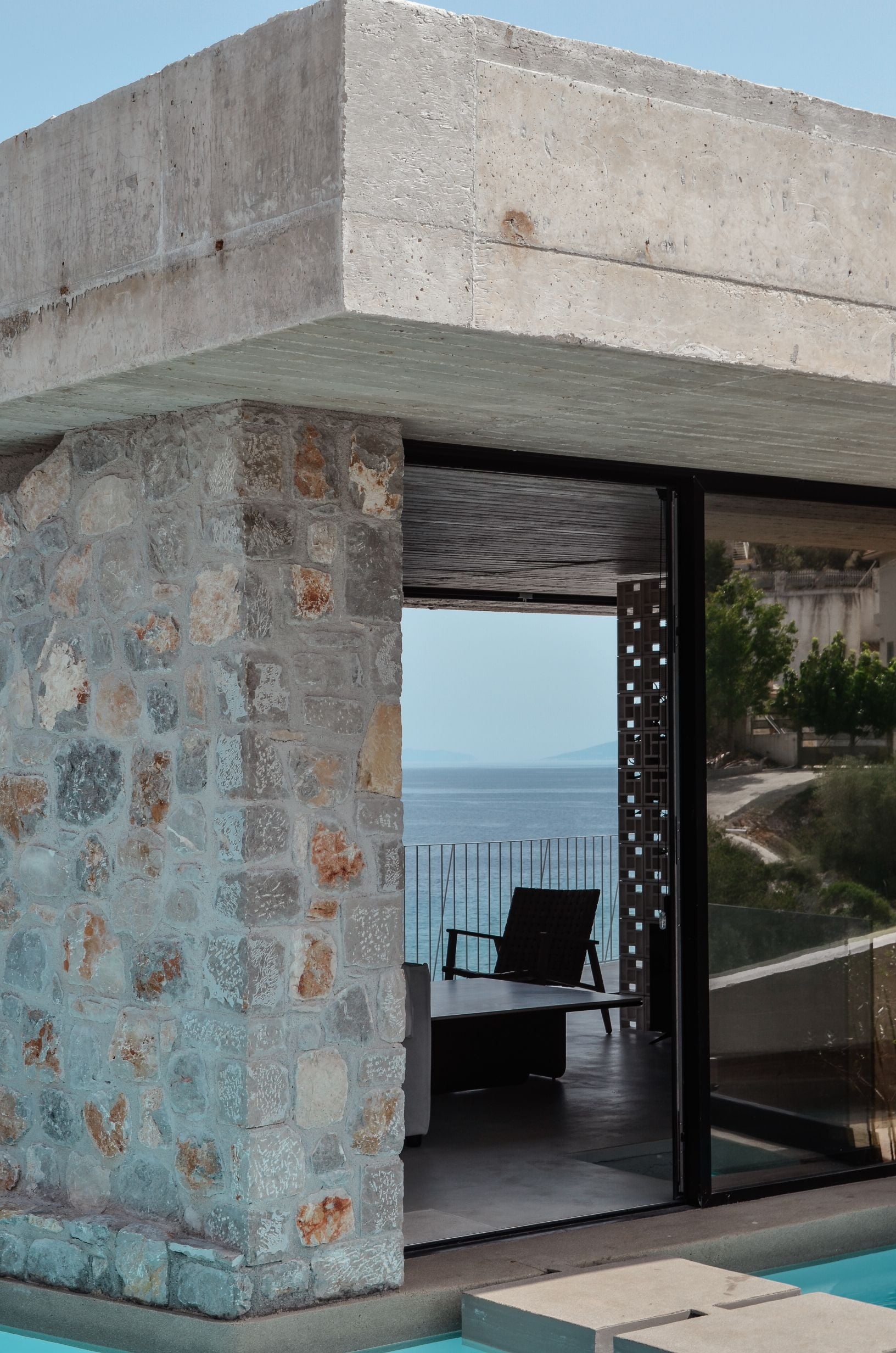 Concrete-framed entrance opening toward the sea — Amoni
