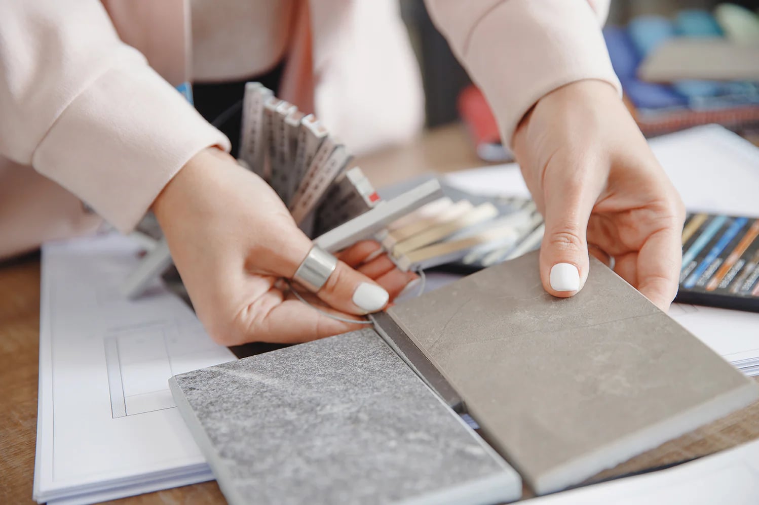 Hands comparing tile and surface samples on a worktable