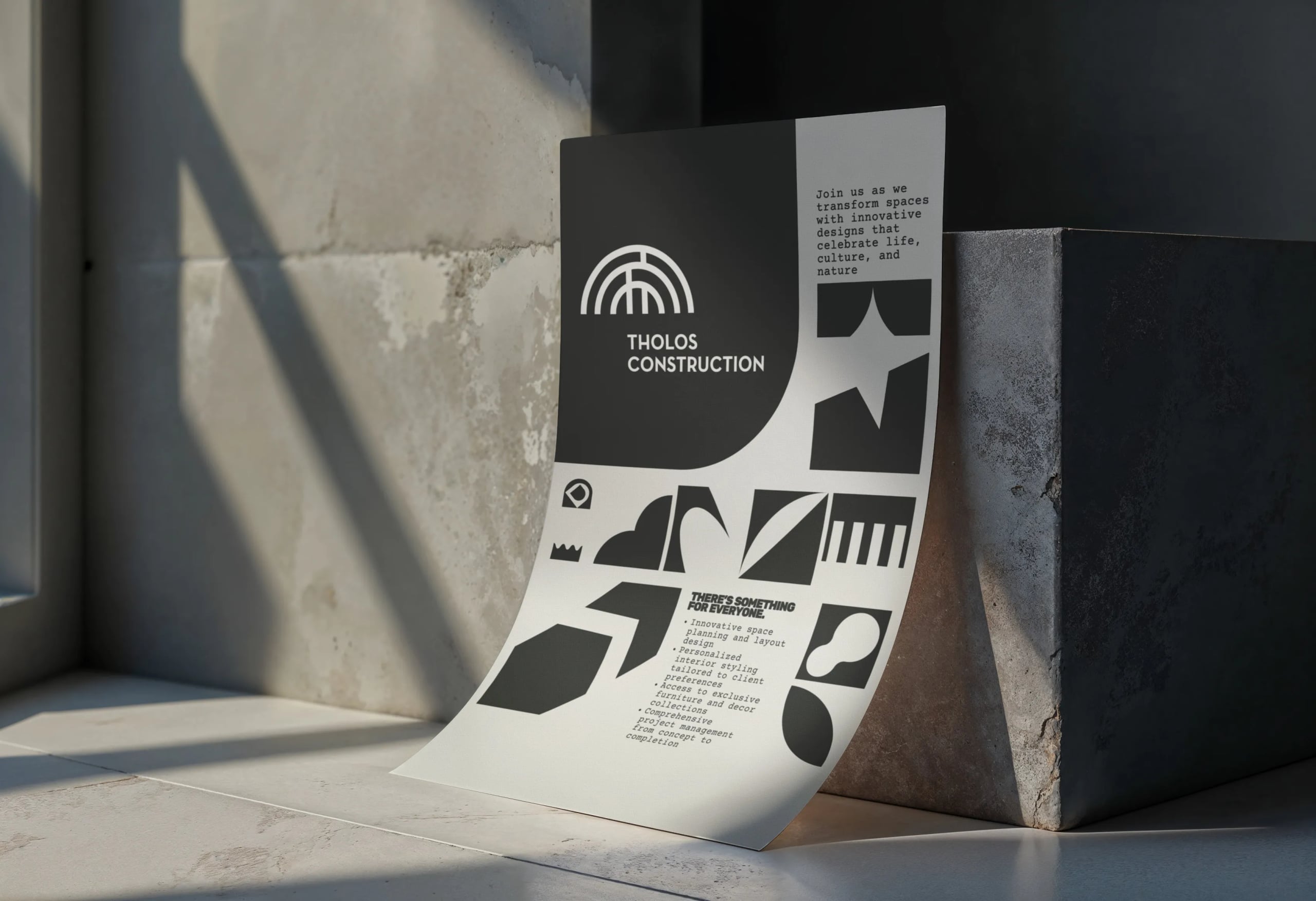 Tholos Construction brochure displayed beside a pale curved object
