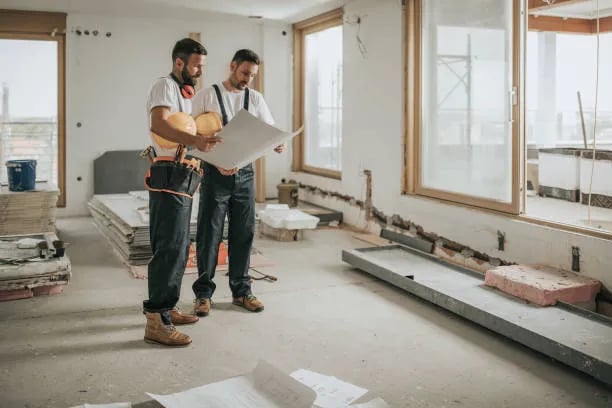 Two people consulting a drawing at an interior construction site